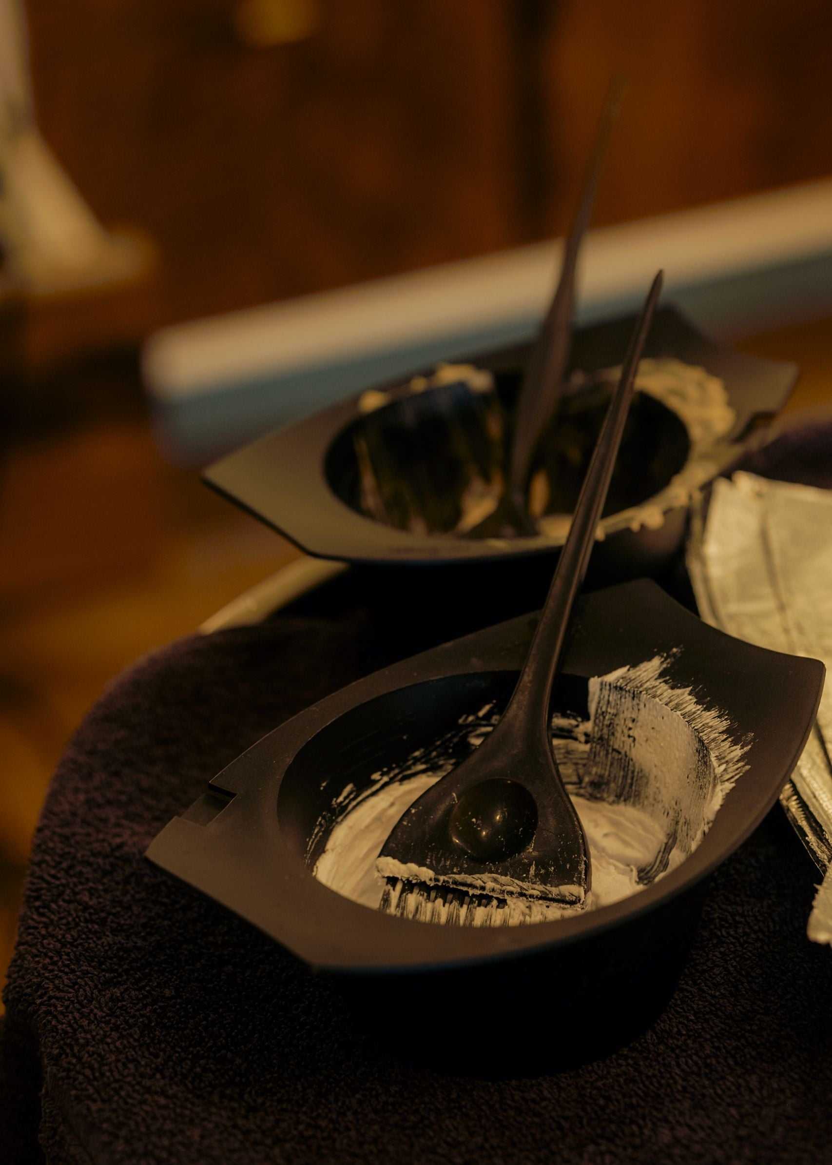 Two black bowls with hair dye and brushes on a table. Ready for hair coloring.