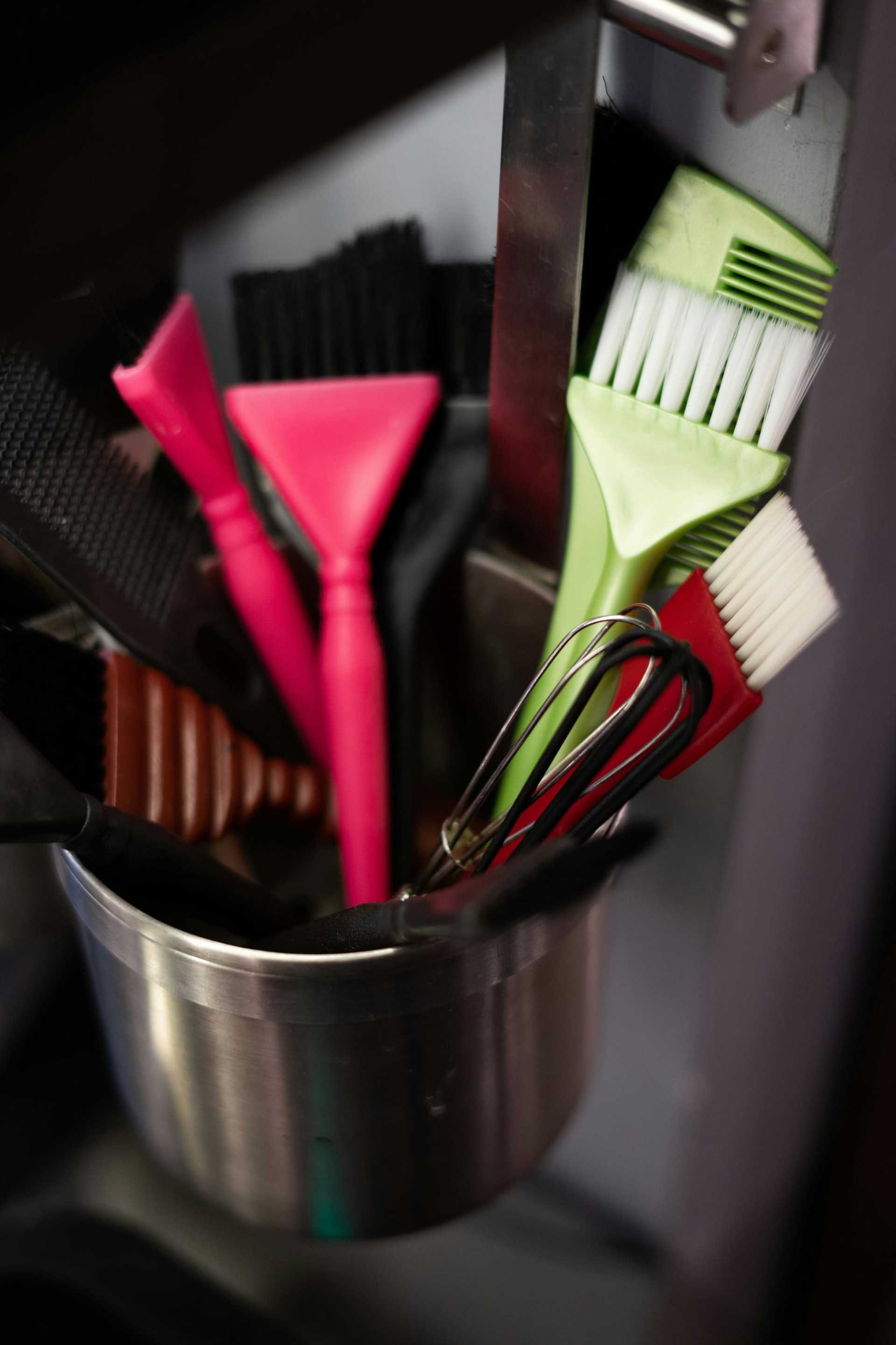Assorted cleaning brushes and squeegees in a metal holder.