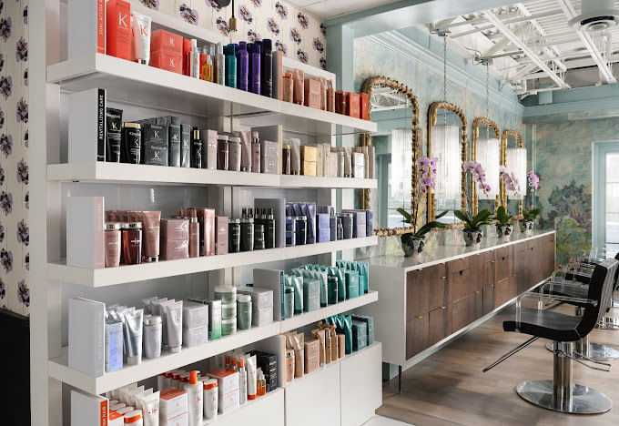 Elegant salon interior with shelves of hair products and stylish mirror stations.