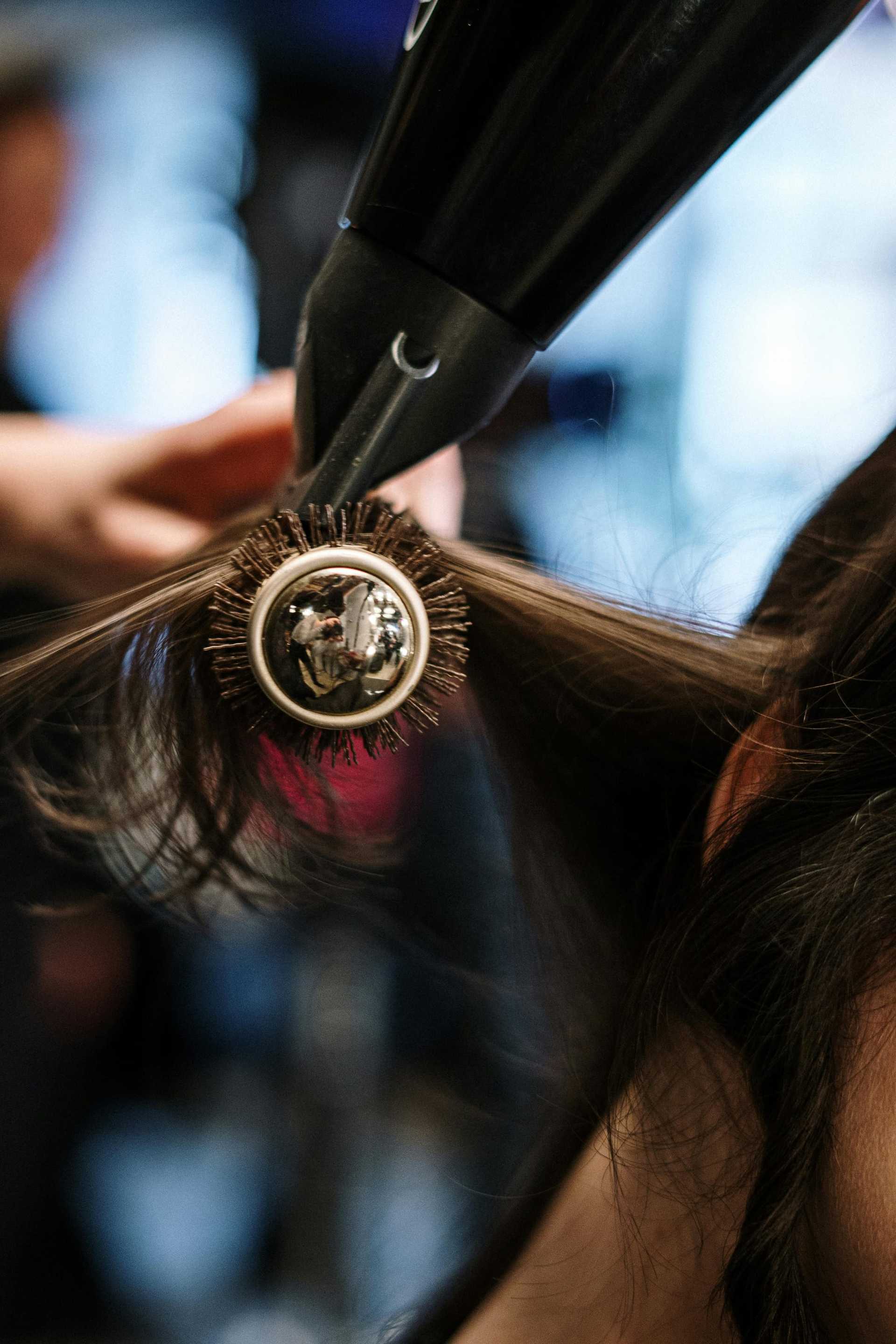 Hair being styled with a round brush and hairdryer.